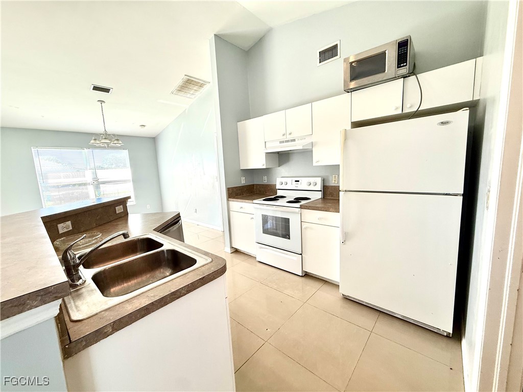 2911 40th Street Southwest Lehigh Acres, FL 33976 - Photo 9 of 22 a kitchen with a refrigerator a stove top oven and a counter top space