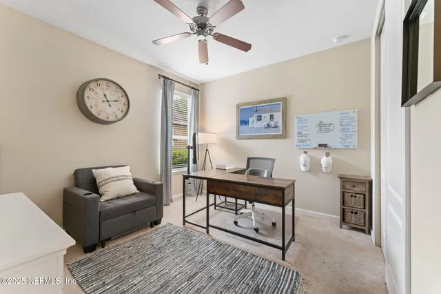 a living room with furniture a clock on wall and a window
