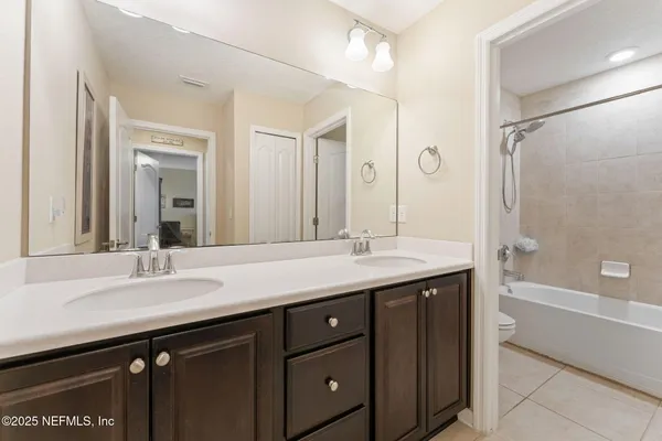 a bathroom with a sink double vanity granite tub shower and a mirror