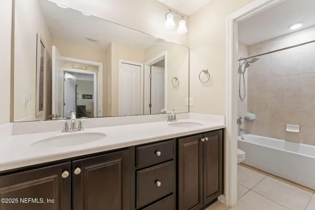 a bathroom with a sink double vanity granite tub shower and a mirror