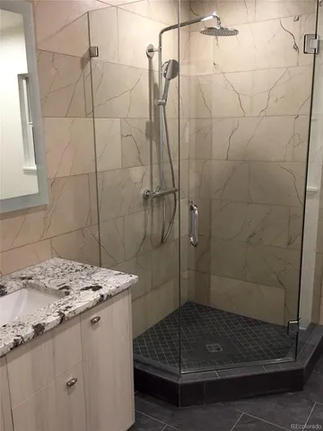 a bathroom with a granite countertop shower a sink and vanity
