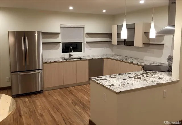 a kitchen with stainless steel appliances kitchen island granite countertop a refrigerator and a sink
