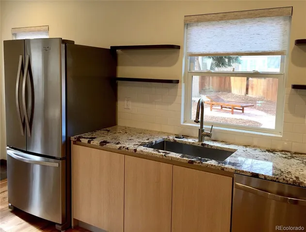 a kitchen with granite countertop a refrigerator and a sink
