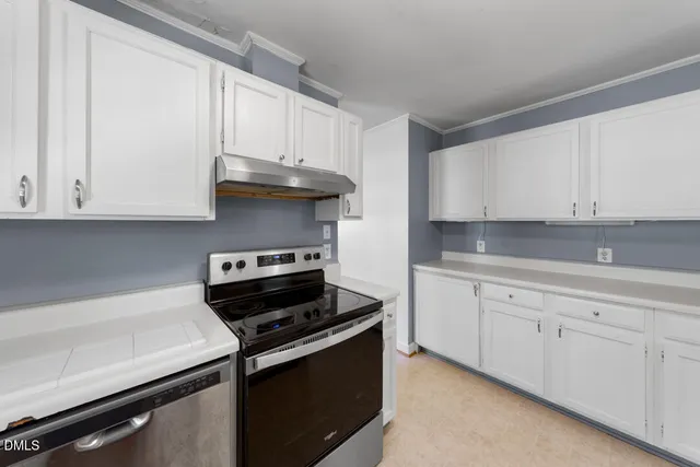 a kitchen with granite countertop white cabinets and stainless steel appliances
