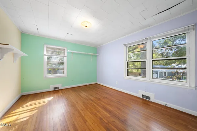 a view of an empty room with wooden floor and a window