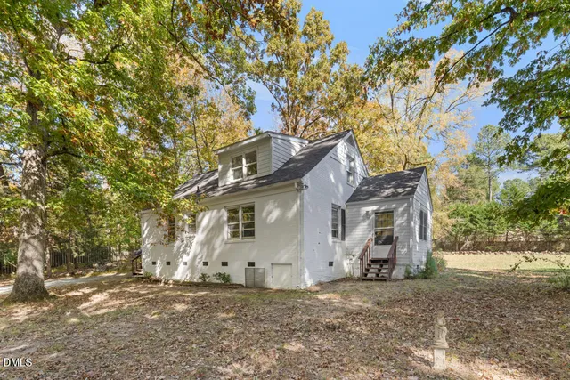 a view of a white house with a large tree next to a road