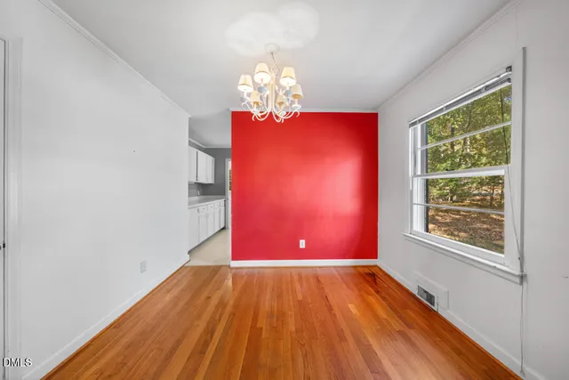 a view of a room with wooden floor a chandelier and windows
