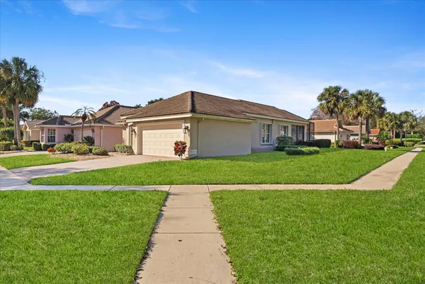 a view of house with a big yard and potted plants