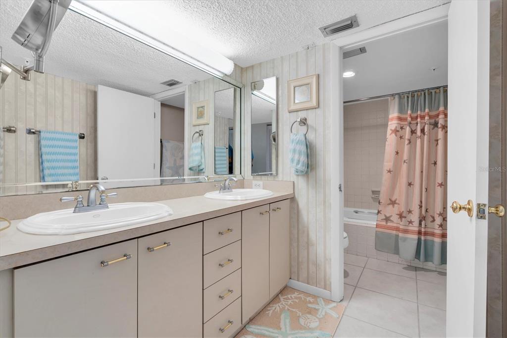 14950 Gulf Boulevard, Unit 402 Madeira Beach, FL 33708 - Photo 14 of 36 a bathroom with a double vanity sink mirror and shower