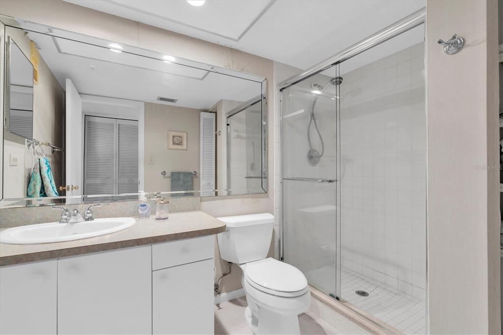 14950 Gulf Boulevard, Unit 402 Madeira Beach, FL 33708 - Photo 18 of 36 a bathroom with a shower sink vanity mirror and toilet