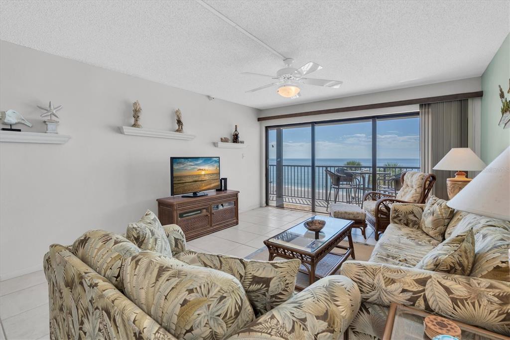 14950 Gulf Boulevard, Unit 402 Madeira Beach, FL 33708 - Photo 3 of 36 a living room with furniture flat screen tv and a large window