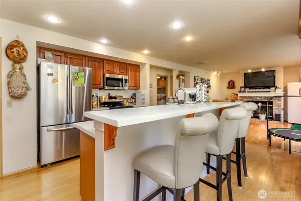 a kitchen with stainless steel appliances granite countertop a refrigerator a stove a microwave a dining table and chairs with wooden floor