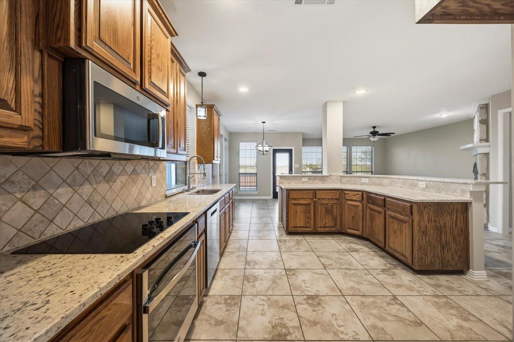 118 Stone Drive Forney, TX 75126 - Photo 4 of 26 a kitchen with stainless steel appliances granite countertop a stove a sink and a microwave