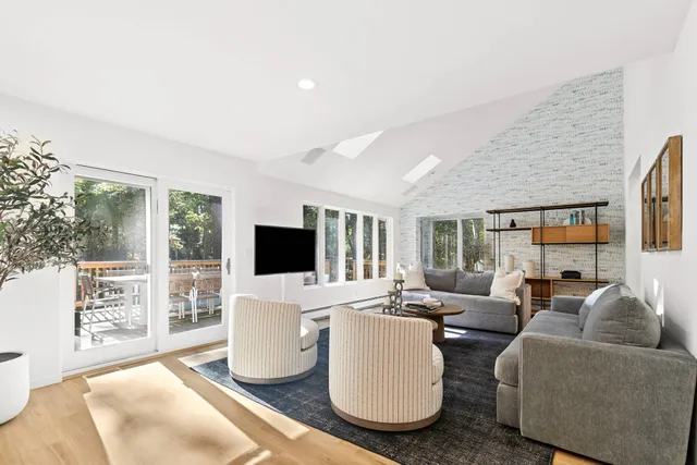 a living room with furniture a flat screen tv and a large window