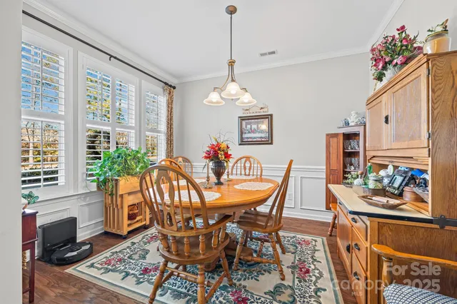 a dining room with wooden floor a chandelier a wooden table and chairs