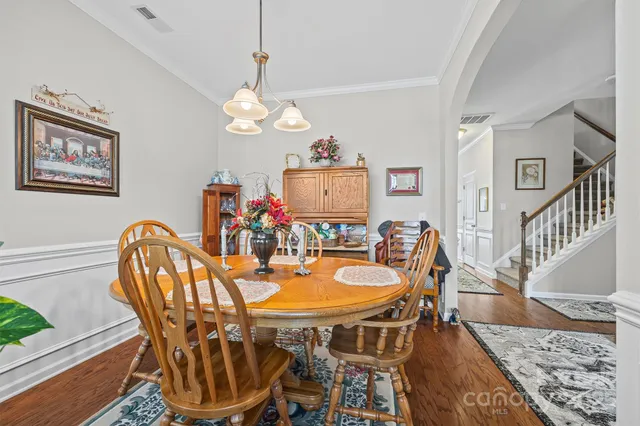a kitchen with stainless steel appliances granite countertop wooden cabinets a sink a stove a dining table and chairs