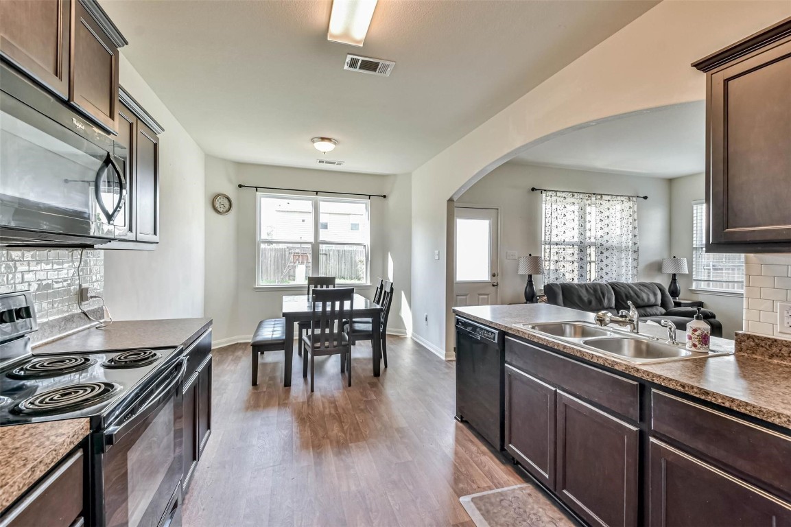 2050 Wilde Elm Houston, TX 77090 - Photo 8 of 19 a kitchen with stainless steel appliances granite countertop a stove top oven a sink a dining table and chairs with wooden floor