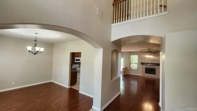 a view of a hallway with wooden floor and chandelier
