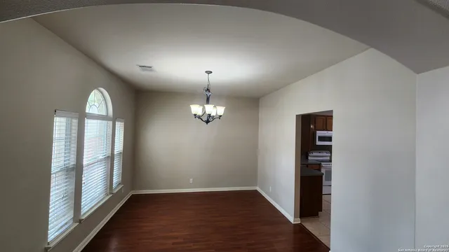 an empty room with wooden floor mirror and windows