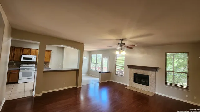 an empty room with wooden floor a fireplace and windows