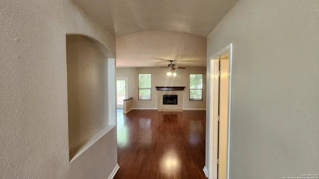 a view of a hallway to an empty room with wooden floor and a cabinet