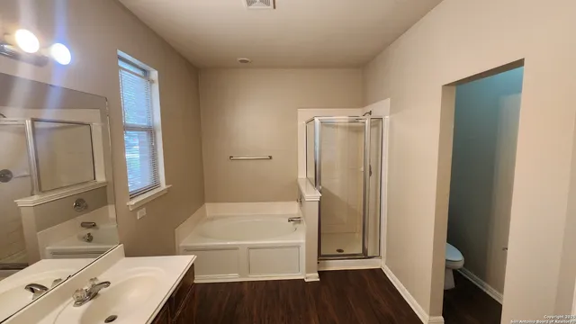 a bathroom with a tub shower vanity and a sink