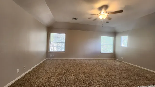 an empty room with windows and fan