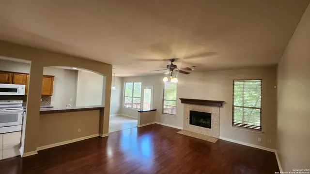 an empty room with wooden floor a fireplace and windows