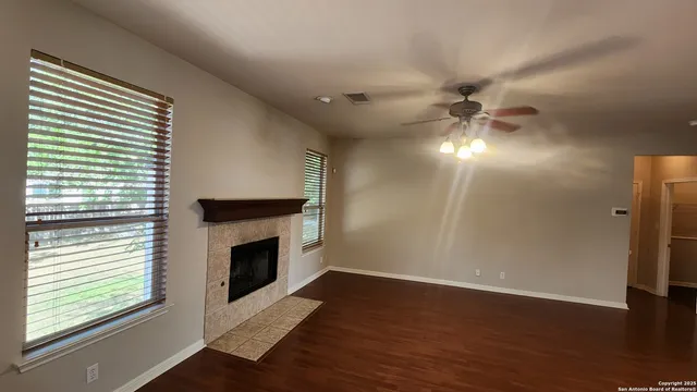 an empty room with wooden floor fireplace and windows