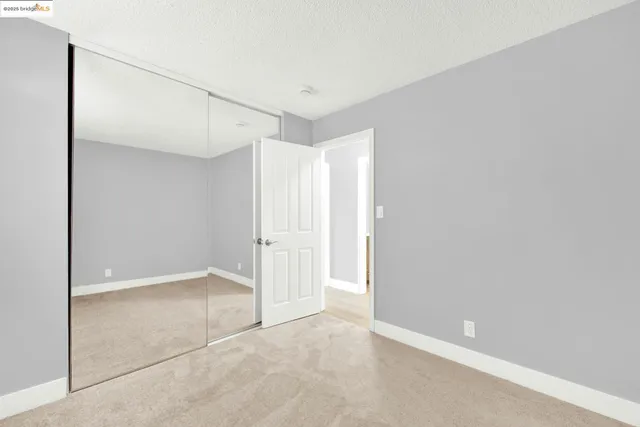a view of an empty room with window and chandelier fan
