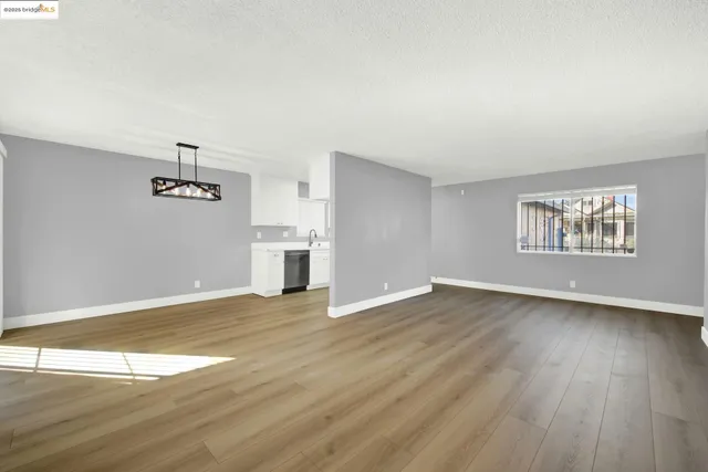 an empty room with wooden floor air conditioner and windows
