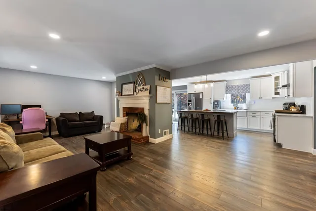 a kitchen with stainless steel appliances granite countertop a stove a sink dishwasher a microwave oven and a dining table with wooden floor