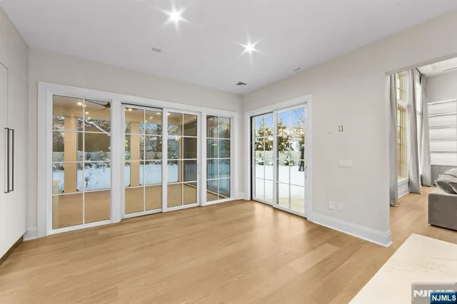 a bedroom with a bed and a lamp on dresser with wooden floor