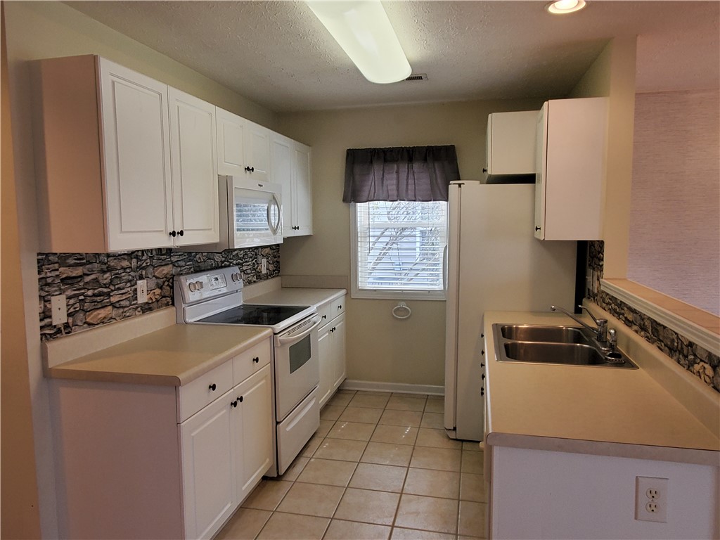 123 Perkins Place Seneca, SC 29678 - Photo 7 of 20 This functional kitchen features white cabinetry, modern appliances, and durable tile flooring.