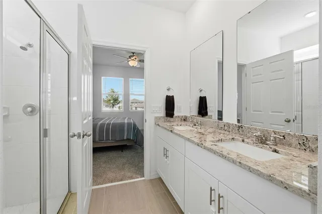 a en suite bathroom with a granite countertop sink and mirror