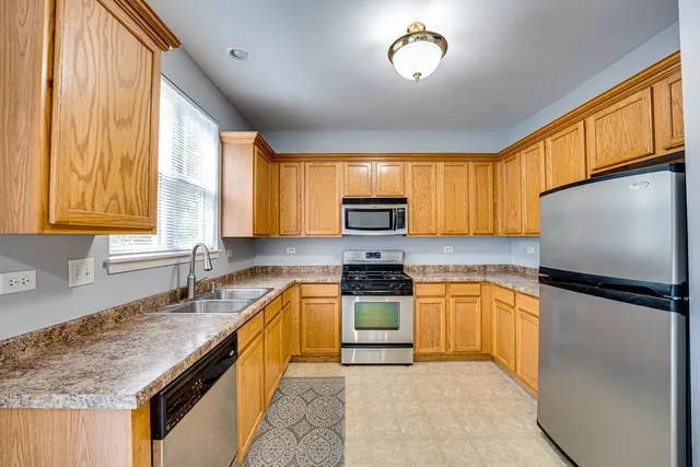 a kitchen with stainless steel appliances granite countertop a stove top oven a sink dishwasher a refrigerator and a microwave