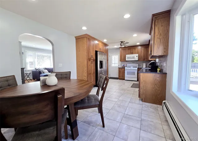 a kitchen with a dining table chairs refrigerator and microwave