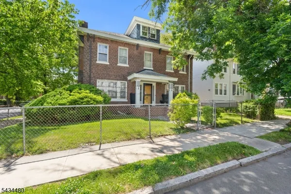 a view of a brick house next to a yard with big trees