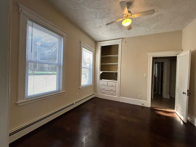 a view of an empty room with a window and wooden floor