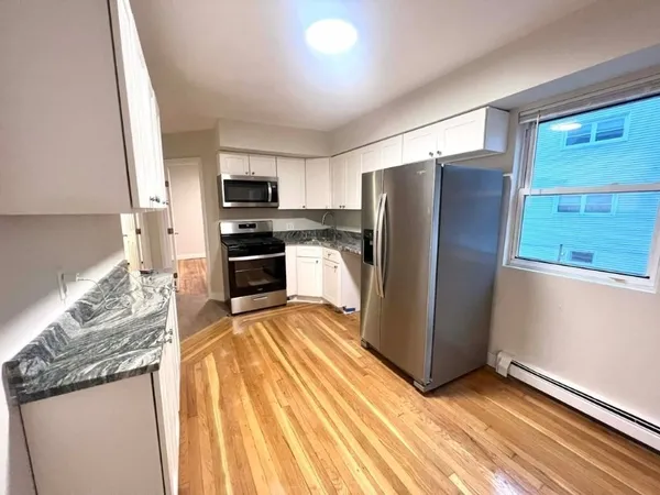 a kitchen with granite countertop stainless steel appliances a refrigerator and a stove top oven