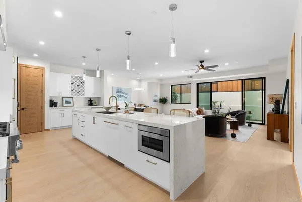 a large kitchen with kitchen island a large counter top a sink stainless steel appliances and cabinets