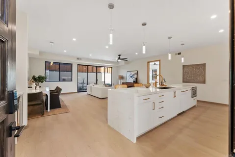 a large white kitchen with kitchen island a sink a center island and stainless steel appliances