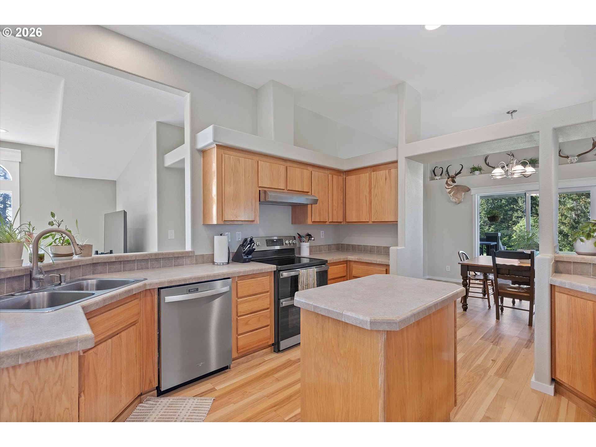 1206 Criteser Loop Toledo, OR 97391 - Photo 11 of 46 a kitchen with stainless steel appliances a sink dishwasher a stove a dining table and chairs with wooden floor