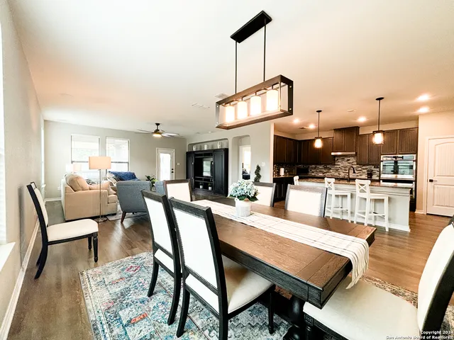 a dining room with wooden floor a chandelier a wooden table and chairs