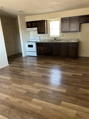 a large kitchen with stainless steel appliances wooden floor and a counter top space