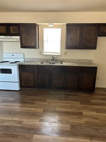 a kitchen with granite countertop a sink cabinets and stainless steel appliances