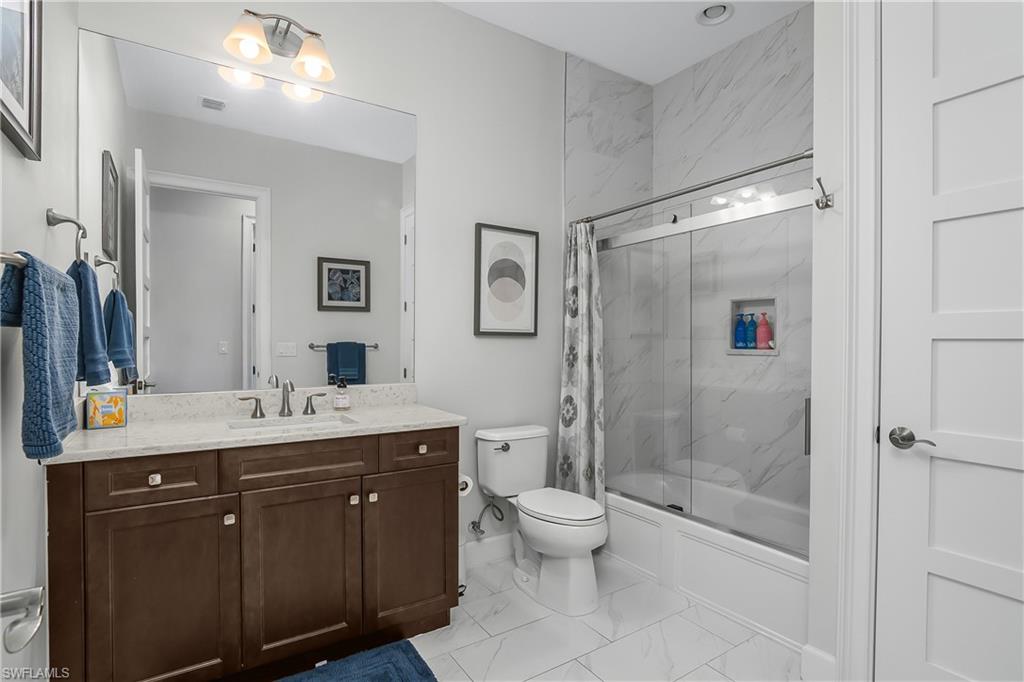 6907 Cay Court Naples, FL 34113 - Photo 18 of 50 Guest Bathroom with vanity, enclosed tub / shower combo, and light marble finish flooring