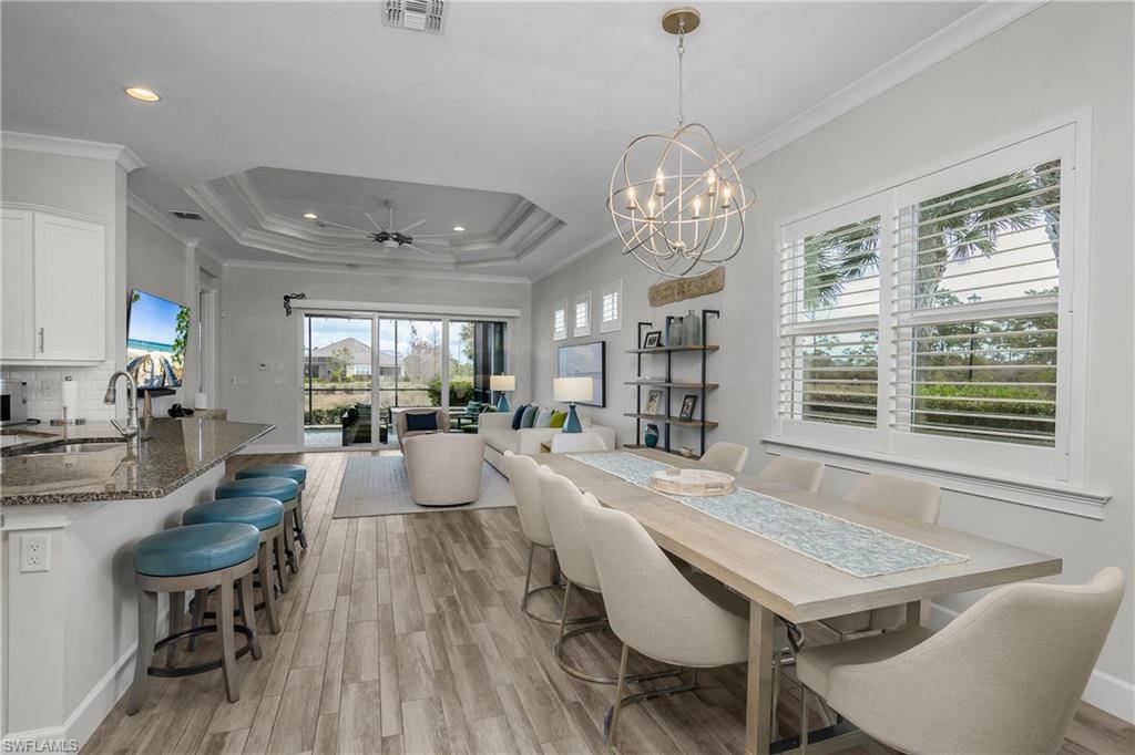 6907 Cay Court Naples, FL 34113 - Photo 24 of 50 Dining space with a ceiling fan, crown molding, a chandelier, and a raised ceiling, Plantation Shutters