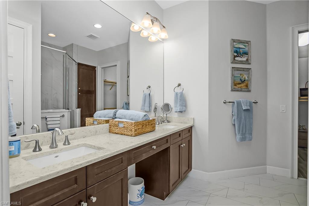 6907 Cay Court Naples, FL 34113 - Photo 27 of 50 Owner's bathroom with double vanity, a stall shower, light marble finish flooring, and a spacious closet