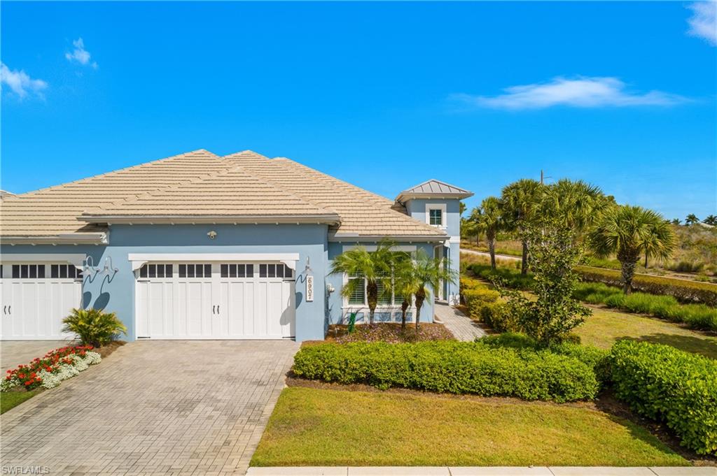 6907 Cay Court Naples, FL 34113 - Photo 37 of 50 View of front of house with decorative driveway, a garage, stucco siding, a front lawn, and a tile roof. No neighbors on the right!